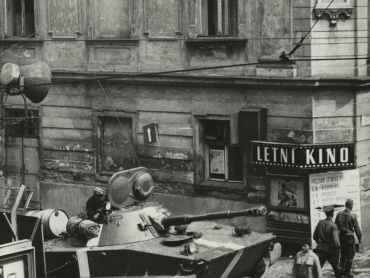 Sovětský tank na křižovatce třídy 1. máje s ulicí Pekární, střežící sovětské vojenské velitelství města Olomouce umístěné v Domě armády, třída 1. máje 3. Státní okresní archiv v Olomouci.